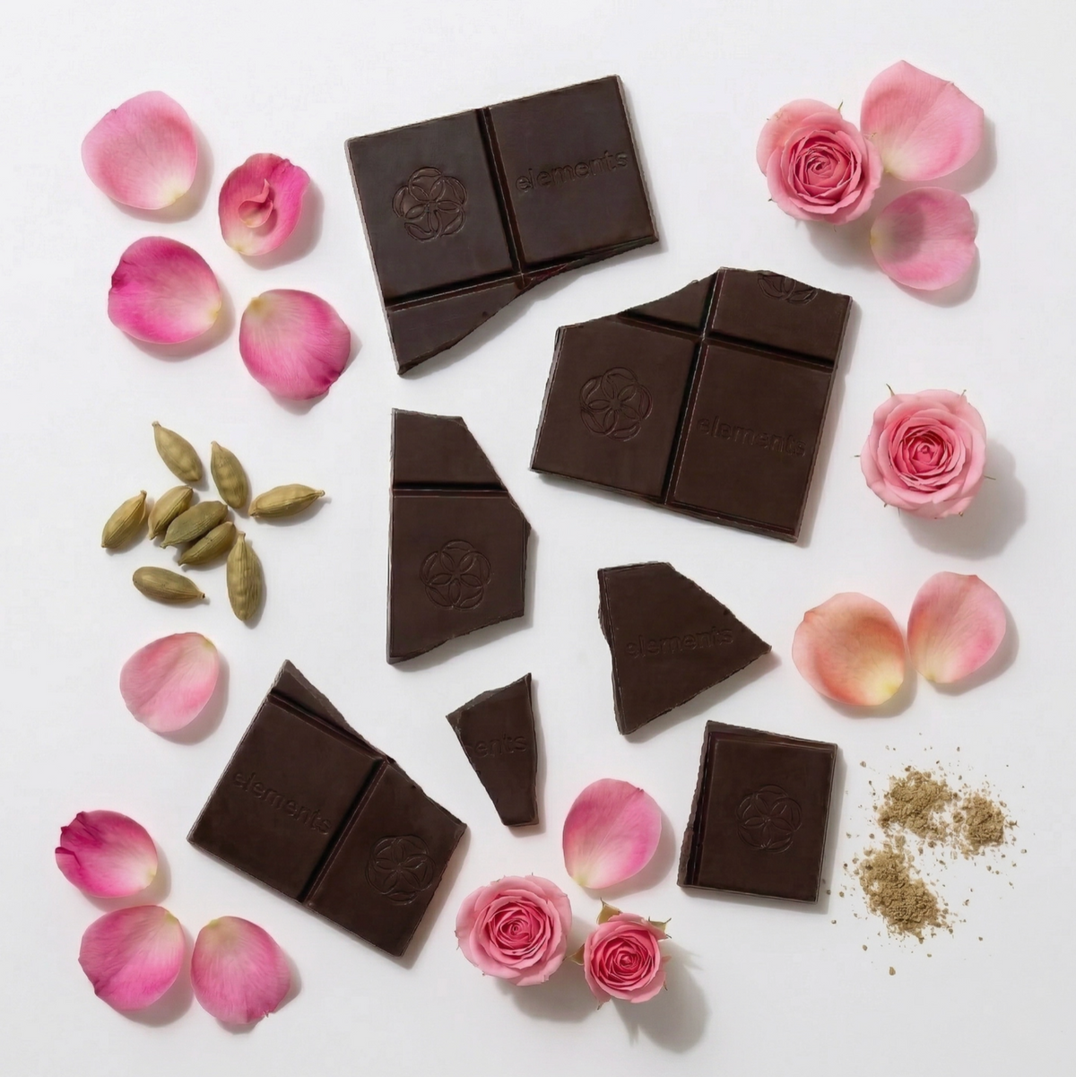 Pieces of broken dark chocolate with rose petals and blooms and cardamom pods