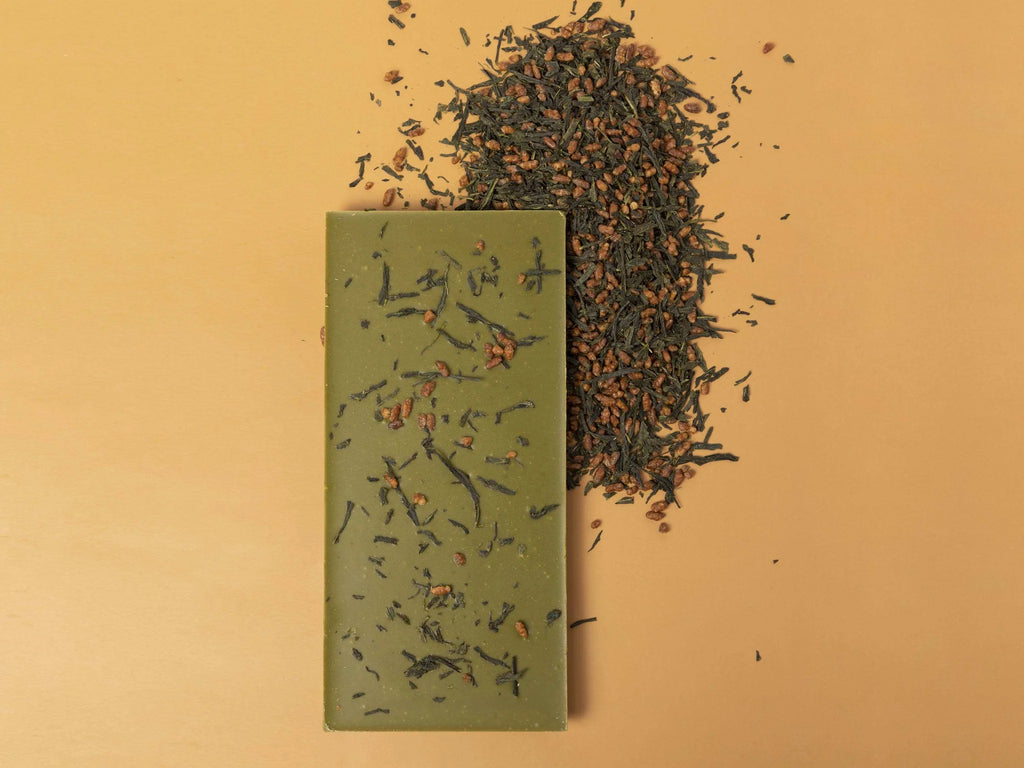 Unwrapped Genmaicha White Chocolate bar from KESSHŌ on a yellow table with genmaicha