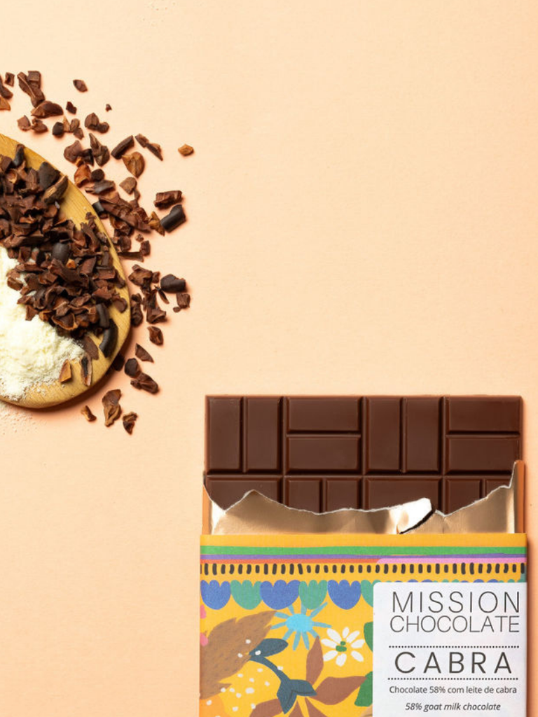 Zoomed in picture of a partially opened Dark Goat Milk Chocolate 58% bar with ingredients on a wooden spoon