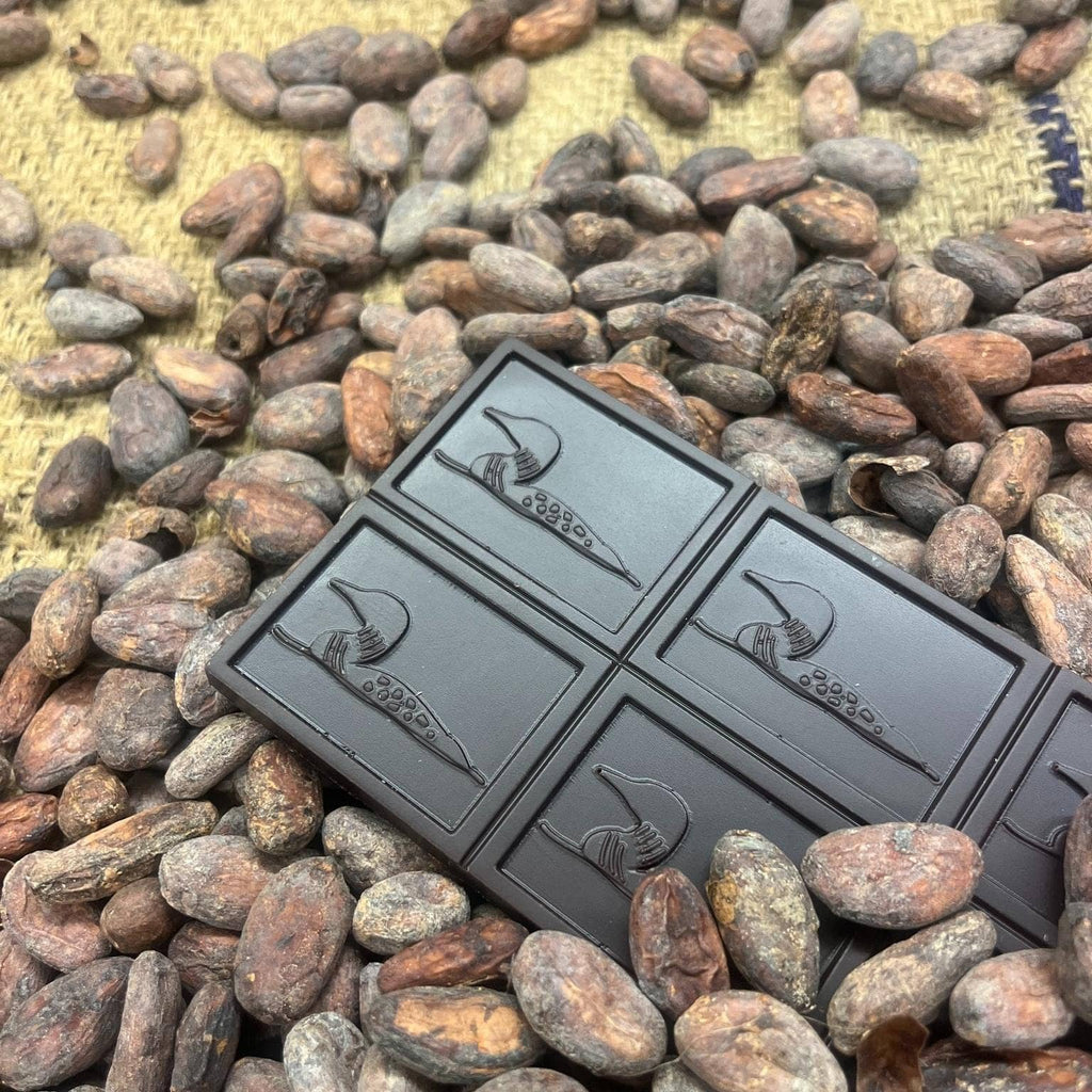 Unwrapped 70% Dark Chocolate w/ Dried Cherry on a bed of cocoa beans