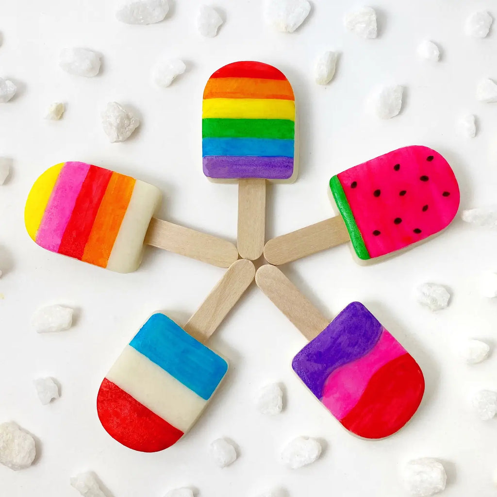 Five unwrapped Marzipan Candy Mini Summer Popsicles on a white table with white candy