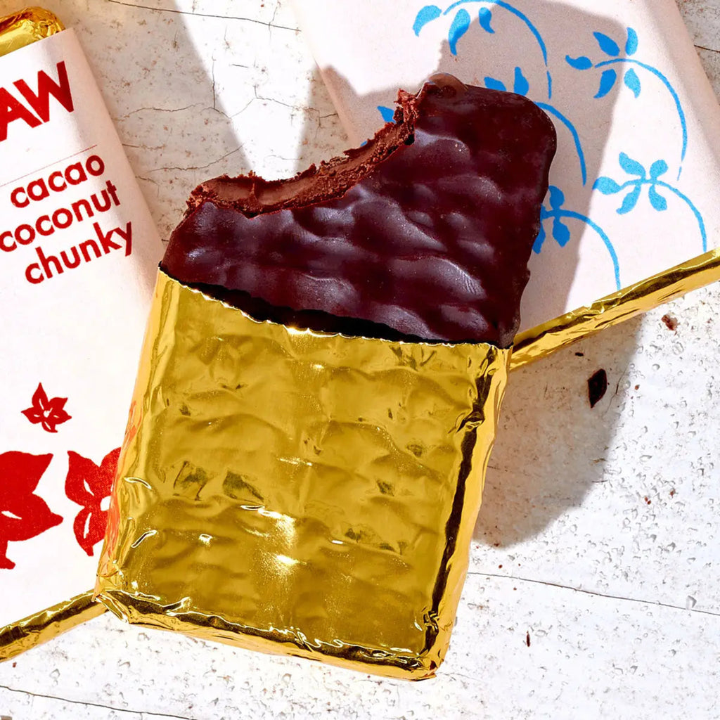 Chocolate bar with gold foil packaging on a white surface with a floral patterned paper.