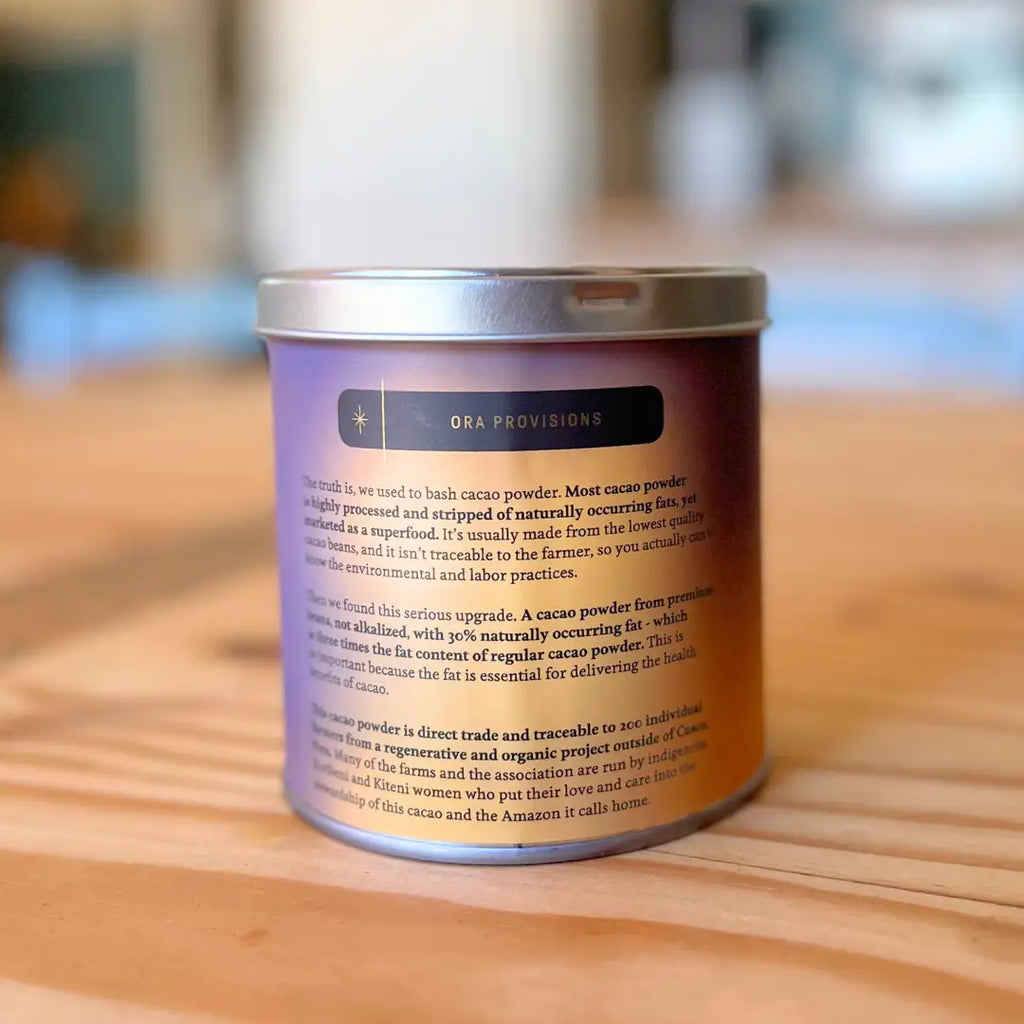 The back of a Ora Provisions Triple Fat Cacao Powder container on a wood counter