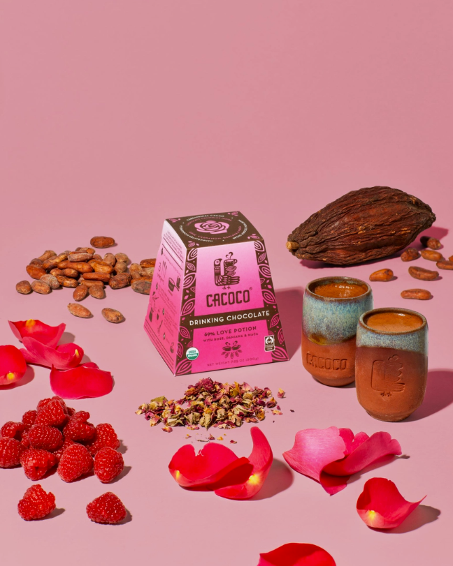 69% Love Potion Drinking Chocolate surrounded by its ingredients on a pink table. 