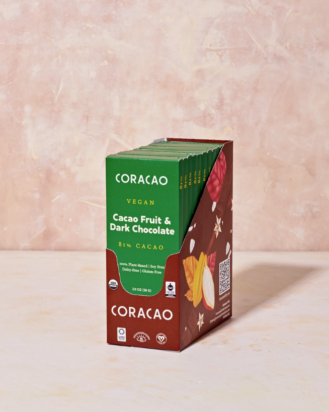 A case of Cacao Fruit & Dark Chocolate bars on a light pink table.