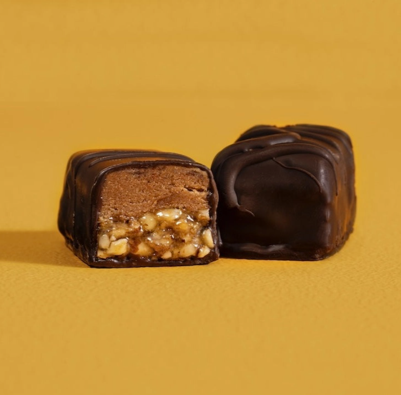 An unwrapped Berkeley Bar broken in half against a yellow background.