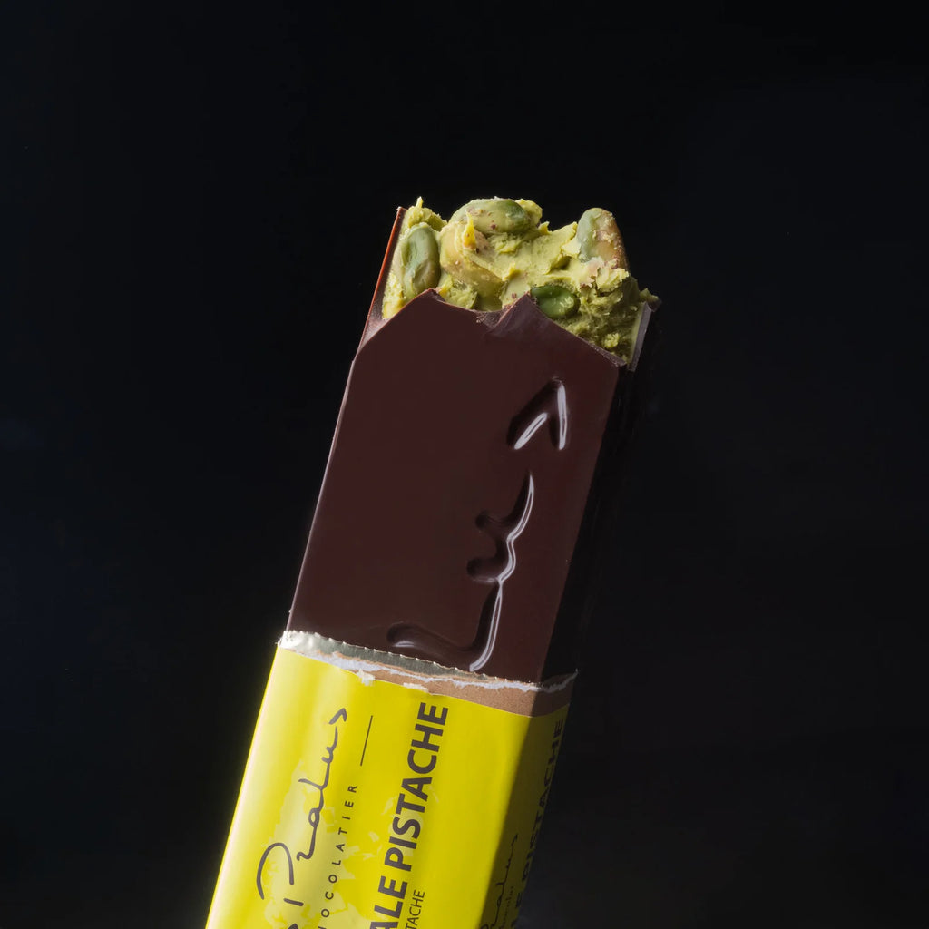 Partially unwrapped 75% Dark Chocolate with Pistachio bar against a black background