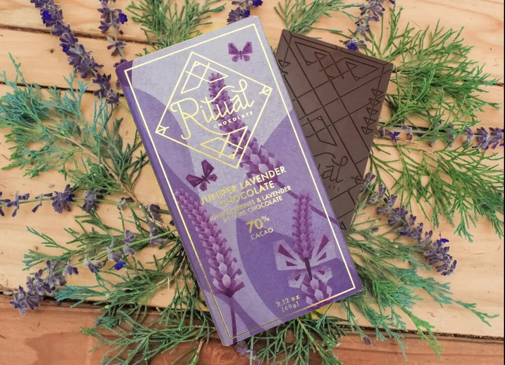 Ritual Chocolate Juniper Lavender Chocolate Bar and package against a wood table with juniper berries and lavender