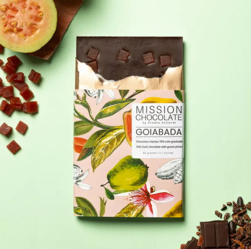 Partially opened Goiabada (Guava) 70% bar on a green table with chocolate ingredients
