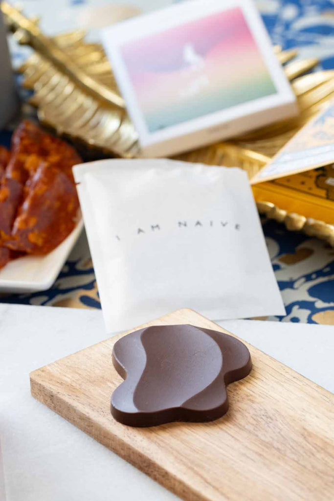 Unwrapped Porcini Dark Milk Chocolate bar on a wooden cutting board