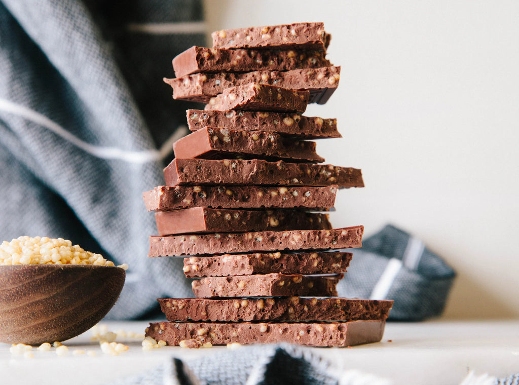 Multiple unwrapped, stacked pieces of Quinoa Crunch 55% Milk bar on a table