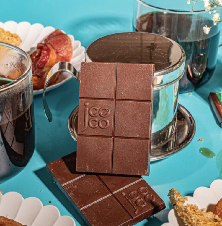 Unwrapped Alaskan Smoked Sea Salt 61% Mini bars on a blue table with various cups and plates of food