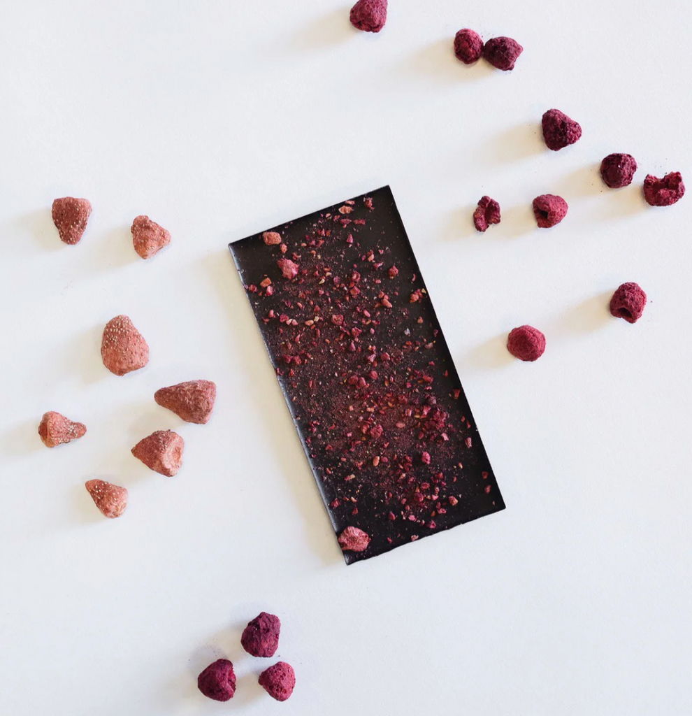 Unwrapped Berry bisous on a white table with various freeze-dried berries