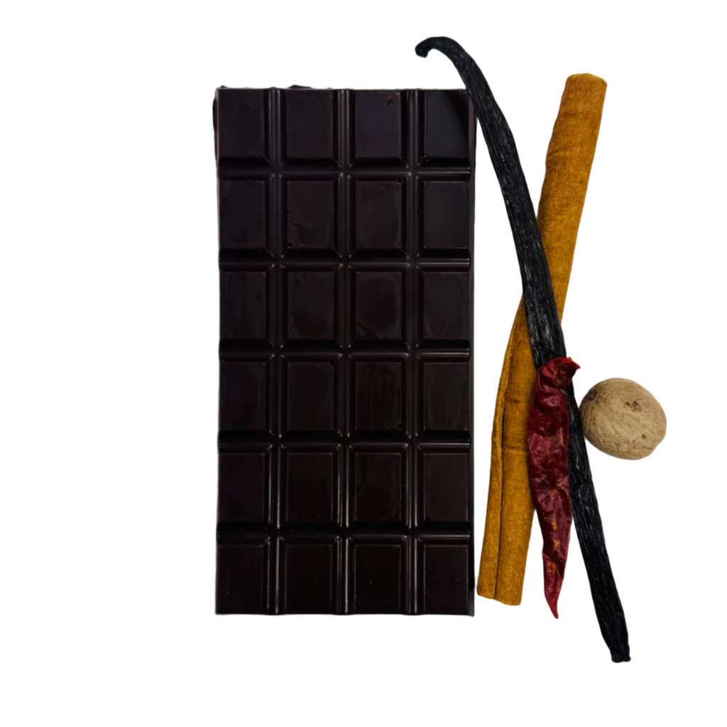 The Organic House Warm spices 65% bar Dark chocolate bar with vanilla bean, cinnamon stick, and nutmeg on a white background