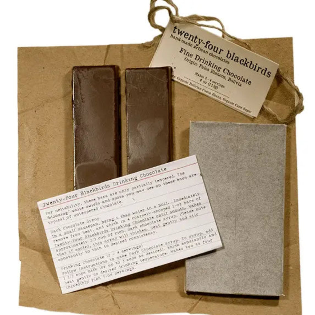 Two bars of 24 black birds drinking chocolate and a card on a brown paper bag against a white background