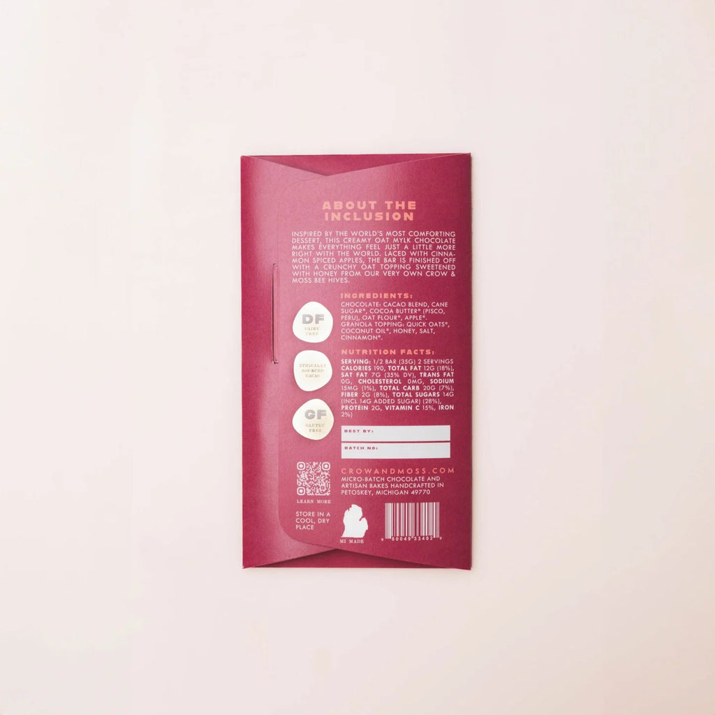 Back Apple Crumble Oat Mylk Bar 38% chocolate bar packaging with nutrition information and ingredients against a light pink background
