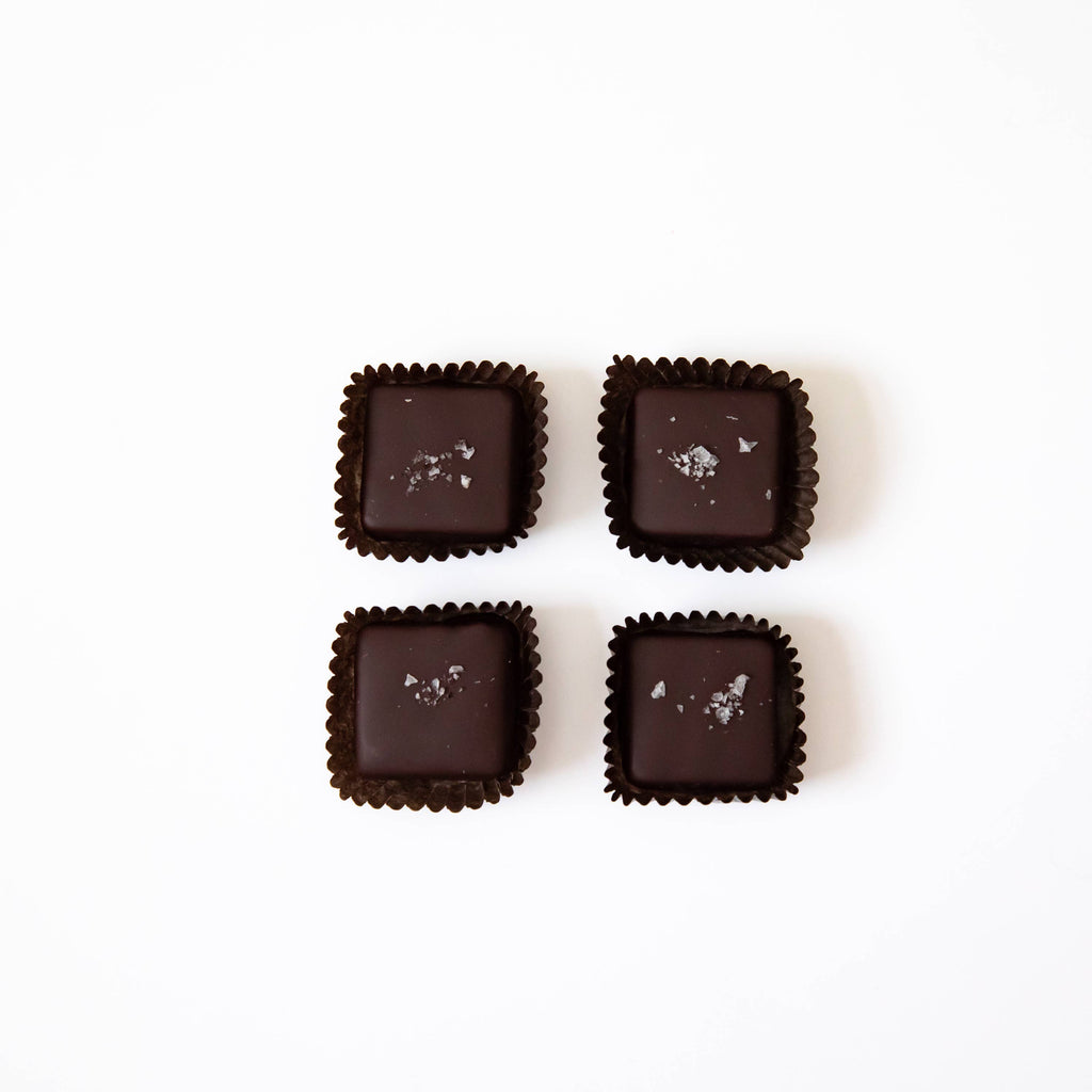 Four unwrapped Salted Caramels from a box of Salted Caramel 4 pcs, against a white background