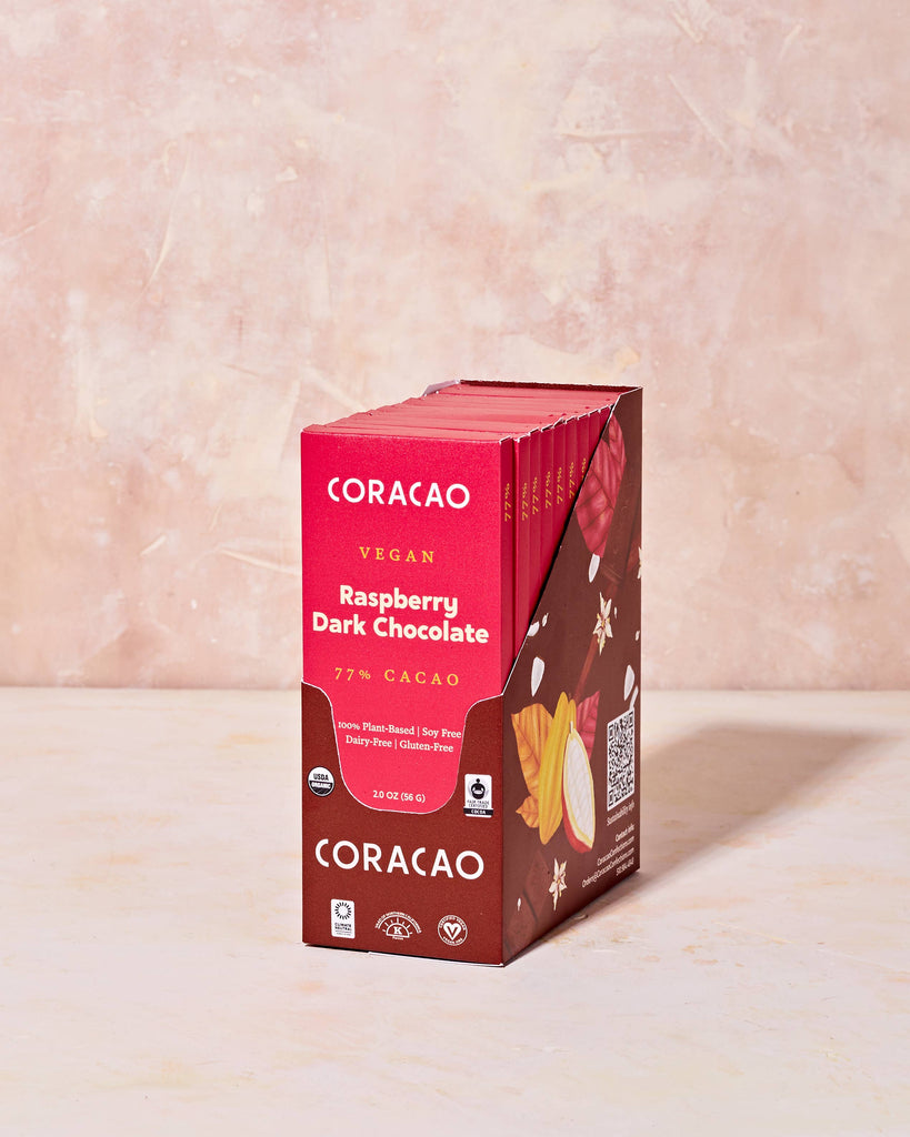 A case of 77% Vegan Raspberry Dark Chocolate bars on a tinted table.