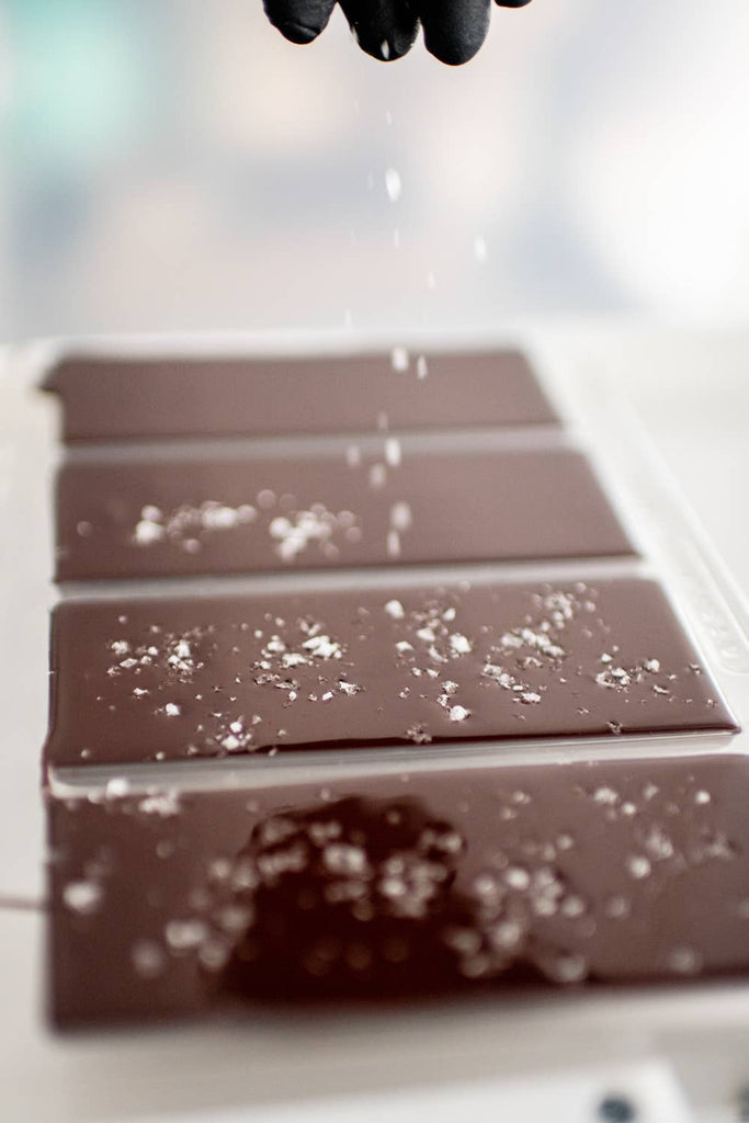 Four 70% Madagascar with Sea Salt bars being salted 