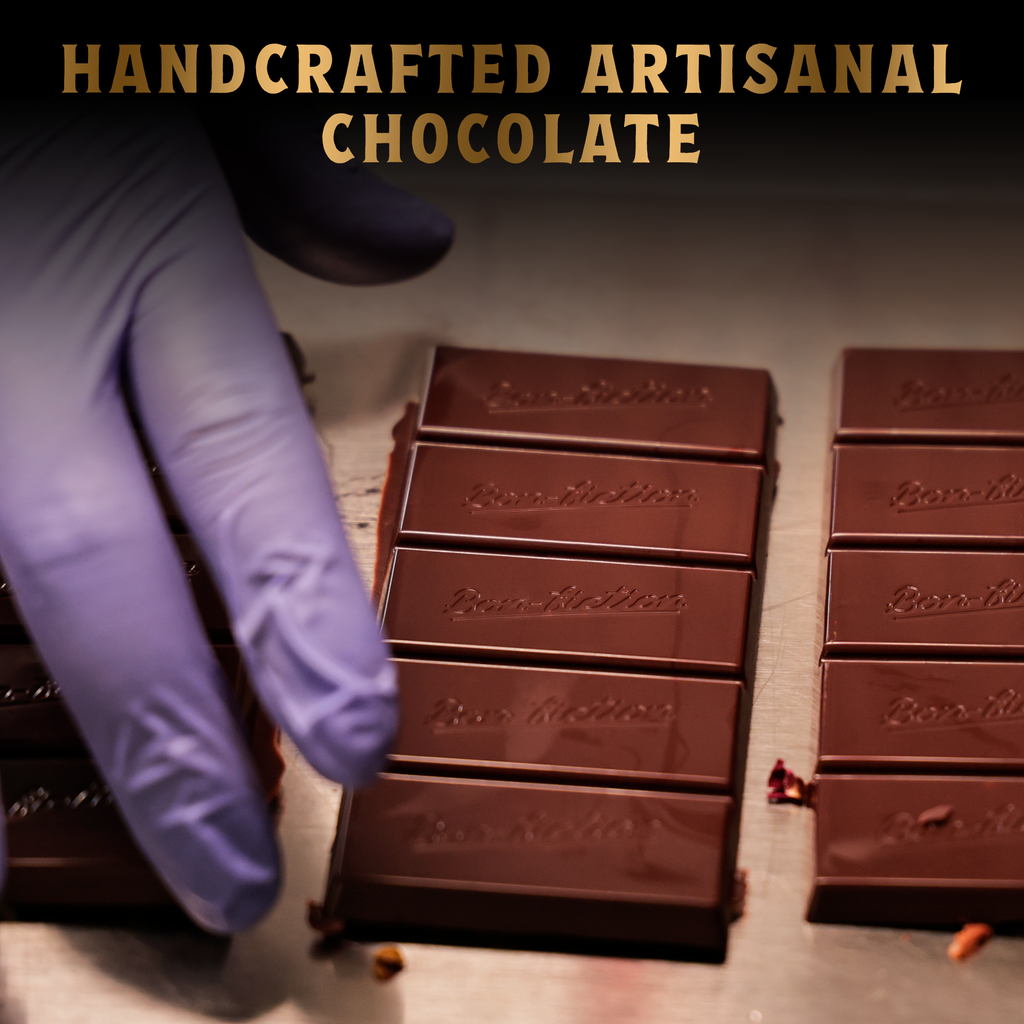 A hand with a rubber glove setting up unwrapped Bon Fiction chocolate bars on a beige table