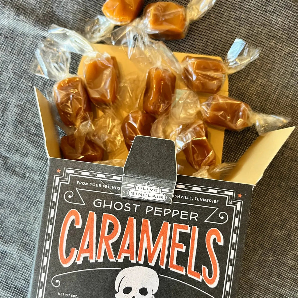 Ghost Pepper Caramels spilling out of box on a gray fabric background
