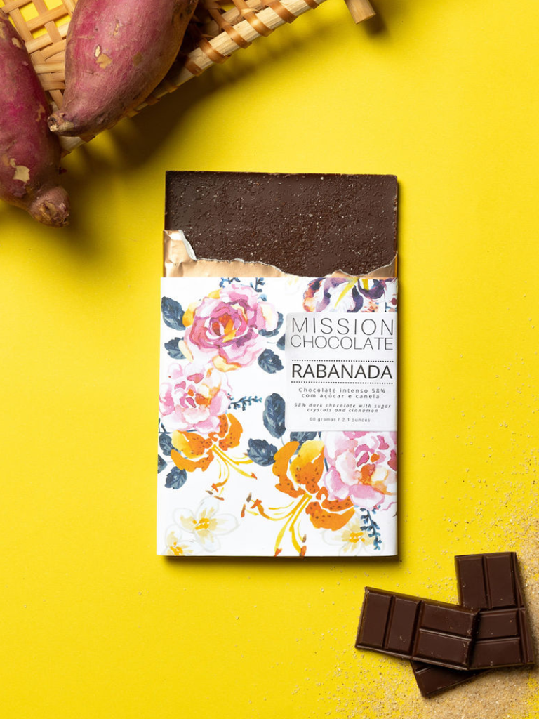 Partially opened French Toast 58% bar against a yellow background with chocolate ingredients