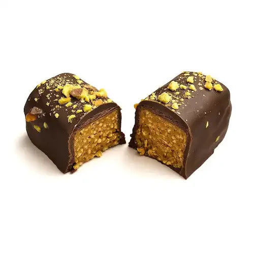 A Dubai Chocolate Bar rom Coracao Chocolate broken in half against a white background